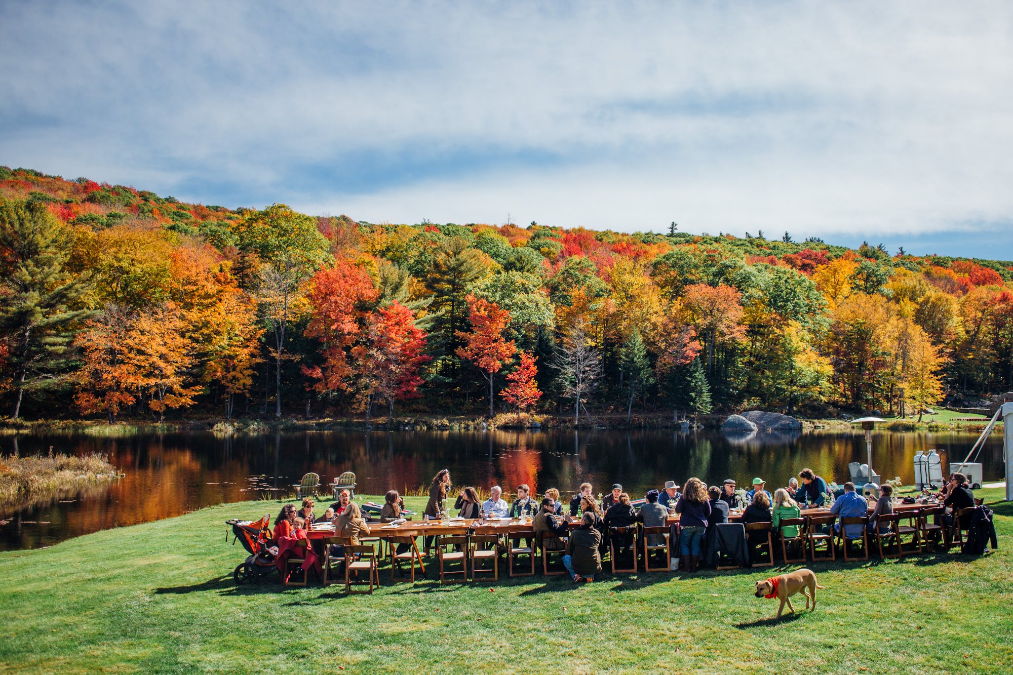 A long table on the Lodge Lawn by the water in fall color